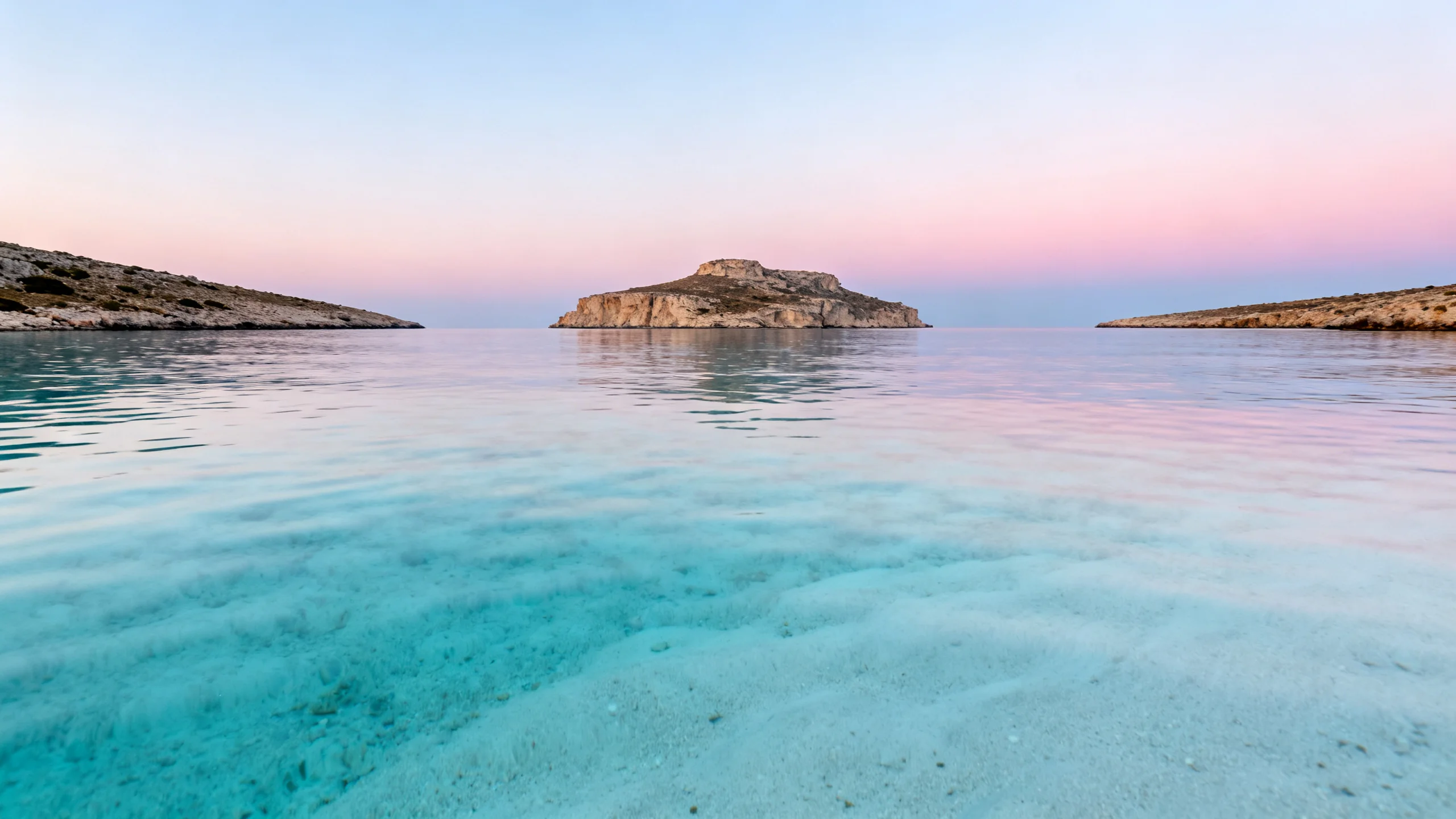 The Blue Lagoon at first light, empty turquoise water between Comino and the limestone islet of Cominotto